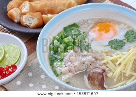 Close up of rice porridge with mined pork and chicken lever served with side dish as Patongko (deep-fried dough stick) and spicy sour filling.