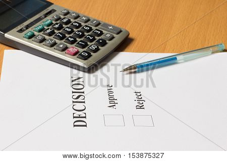 Blue pen calculator and decision paper for approve reject