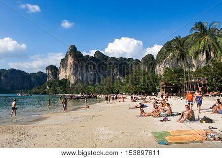 KRABI - JANUARY 20, 2015 : Tourist enjoying a beach walk and sunbathing on a sunny day JANUARY 20, 2015 at Railay Beach in Krabi, Thailand. Railay Beach is a small peninsula with white sand beaches, soaring limestone cliffs, viewpoints, caves and a lagoon