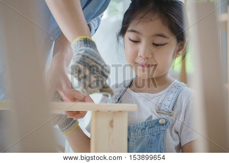 Asian lovely girl helping her mother assembling new DIY furniture at home together