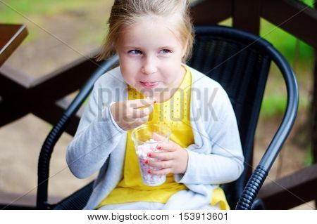 Adorable little girl eating mini marshmallow in park