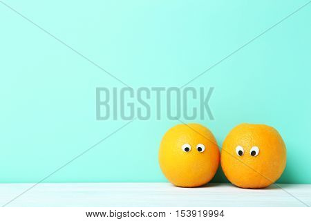 Ripe Oranges With Googly Eyes On Green Background