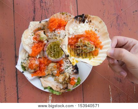 Man hold grilled scallop on wooden table background