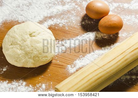 Eggs rolling pin and dough on the wooden table in the kitchen. Ingredients and tools for baking dough. Still life in a rustic style.