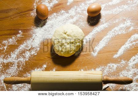 Eggs rolling pin and dough on the wooden table in the kitchen. Ingredients and tools for baking dough. Still life in a rustic style. Easter preparation.