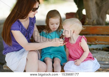 Young mother and her daugthters eating ice cream outdoors