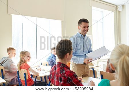 education, school, learning and people concept - group of students and teacher with test results in classroom