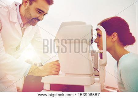 health care, medicine, people, eyesight and technology concept - optometrist with non contact tonometer checking patient intraocular pressure at eye clinic or optics store