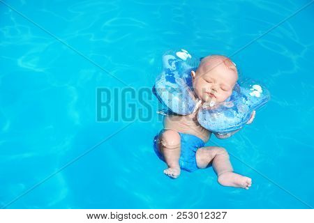 Cute Little Baby With Inflatable Neck Ring In Swimming Pool On Sunny Day, Outdoors