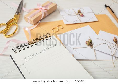 Wedding Preparation.flat Lay And Close Up View Of Checklist And Wedding Invitations On A White Woode