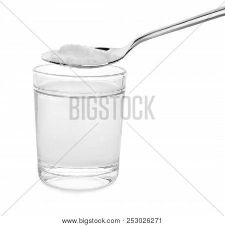 Spoon With Baking Soda Over Glass Of Water On White Background