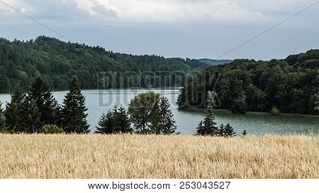 Landscape Of Oat Field And Ostrzyckie Lake, Wiezyca, Kashubian Region, Poland. Nature And Agricultur