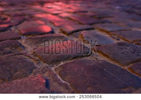 Wet Illuminated By Red Light Cobblestone Street At Night