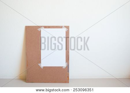 Watercolor Painting Board With Attached Art Paper Leaning On Cement Wall Having Light From Right Sid