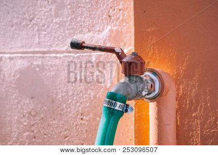 Closeup Water Tap On The Wall Connected With Green Rubber Tube
