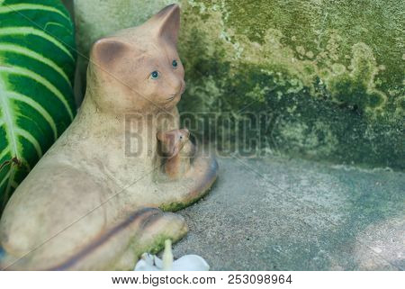 Sculpture Of A Cat Holding A Mouse With Care Near The Old Cement Ladder