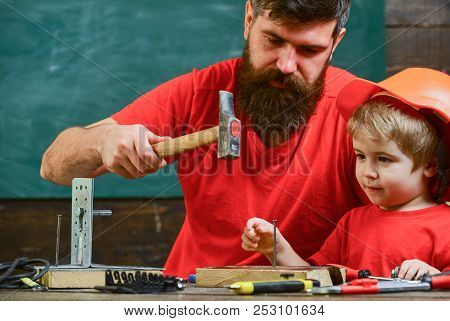 Workshop And Handyman Concept. Boy, Child Busy In Protective Helmet Learning To Hammering Hobnails W