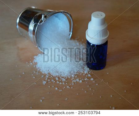 Natural Salt In Silvery Bucket And Blue Etherial Oil Bottle On Weathered Wooden Table