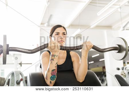 Beautiful Young Woman Doing Biceps Curl With Barbell In Fitness Club