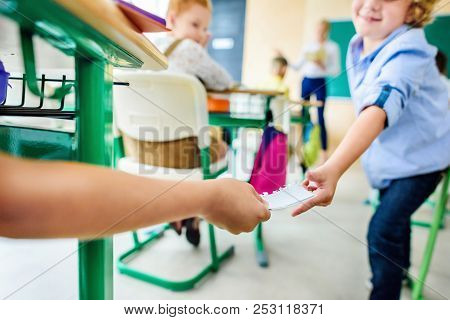 Cropped Shot Of Classmates Passing Message On Paper During Lesson