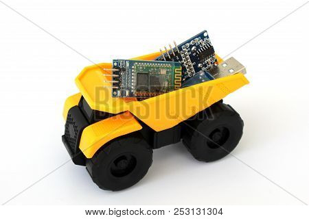 Isolated Toy Truck In Yellow And Black Colors With White Background And Electronic Parts