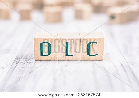 The Word Dlc Formed By Wooden Blocks On A White Table
