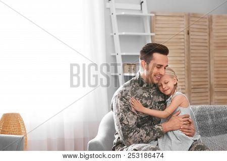 Young Man In Military Uniform With His Little Daughter On Sofa At Home