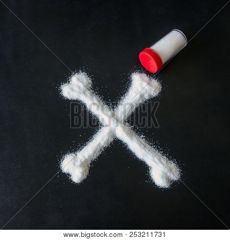 Salt Scattered On Black Surface. Drawn Crossed Bones. Concept-   Diet, Harm To Health From Excessive