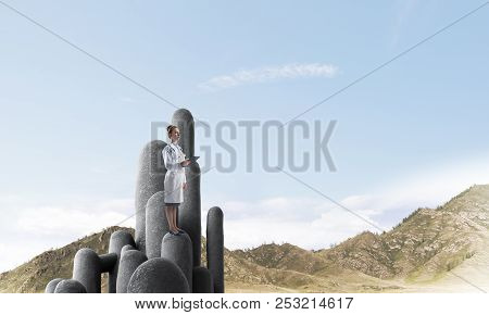 Young Female Doctor With Folder In Hands Satnding On Stone Column
