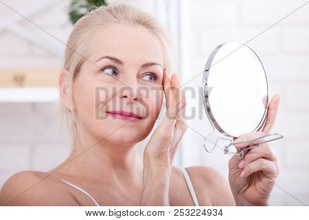 Forty Years Old Woman Looking At Wrinkles In Mirror. Plastic Surgery And Collagen Injections. Makeup