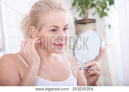 Forty Years Old Woman Looking At Wrinkles In Mirror. Plastic Surgery And Collagen Injections. Makeup