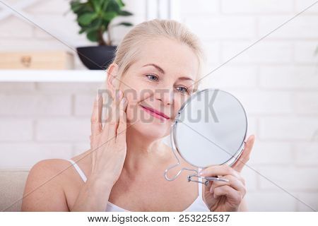 Forty Years Old Woman Looking At Wrinkles In Mirror. Plastic Surgery And Collagen Injections. Makeup