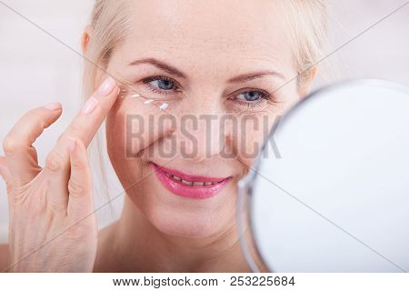 Forty Years Old Woman Looking At Wrinkles In Mirror. Plastic Surgery And Collagen Injections. Makeup