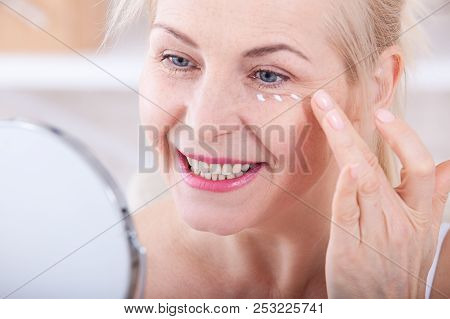 Forty Years Old Woman Looking At Wrinkles In Mirror. Plastic Surgery And Collagen Injections. Makeup