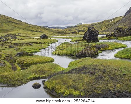 Landscape With Lush Green Grass And Moss, Water Stream And Lagoon And Lava Rock In Iceland Central M
