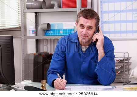 Man aan de telefoon bij een loodgieter handelaars