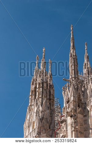 Many Lateral Spiers Surmounted By Statues Of The Milan Cathedral With A Clear And Blue Sky