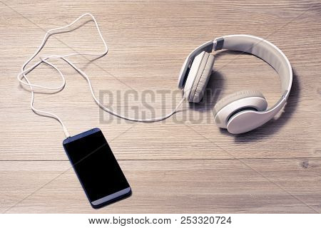 White Headphones And Mobile Phone On A Table