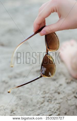 Photo Of Woman's Hand Holding Sunglasses Against Sand