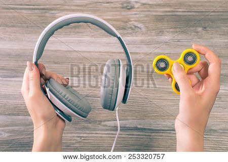 Concept Of Combining Listening To Music And Using Popular Fidget Spinner. Close Up Photo Of Hands Ho