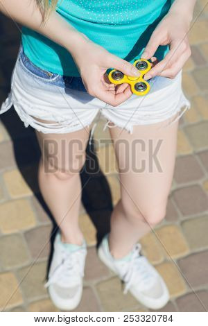 Young Girl Holding Fidget Spinner In Hands While Having A Walk Outdoors