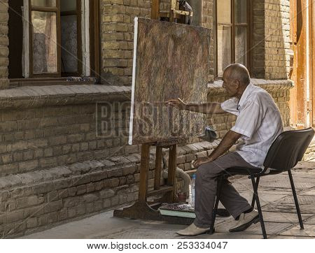 Bukhara, Uzbekistan - Jule 02, 2018: An Old Man Draws An Abstraction With A Paint Brush.
