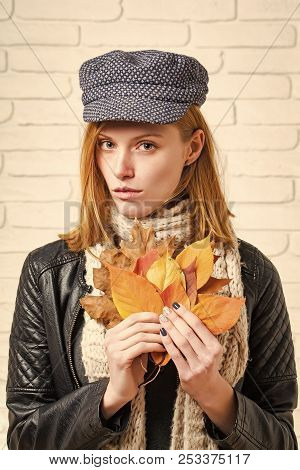 Woman With Autumn Leaves In Leather Jacket. Girl With Orange Leaves At Brick Wall. Season And Autumn