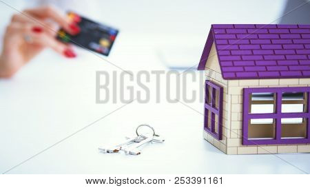 Saleswoman Holds A Credit Card And Calculating A Price Of Selling New Home Loan. Model Private House