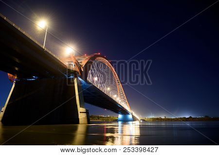 Bridge over the river Ob night. The lights of the bridge glow in the night sky.