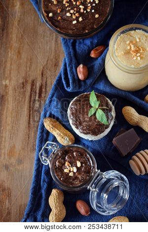 White And Chocolate Peanut Urbech In Glass Jars Surrounded By The Ingredients. Top View