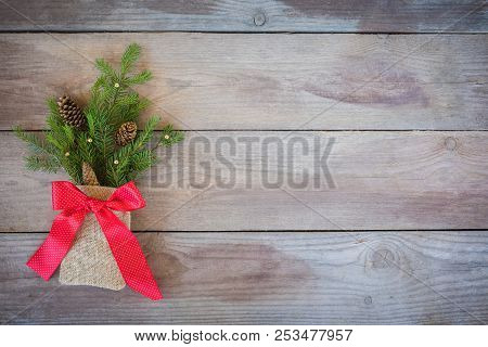 Christmas Firbranch With Cones, Red Polka Dot Ribbon In The Rustic Bag On Old Wooden Background