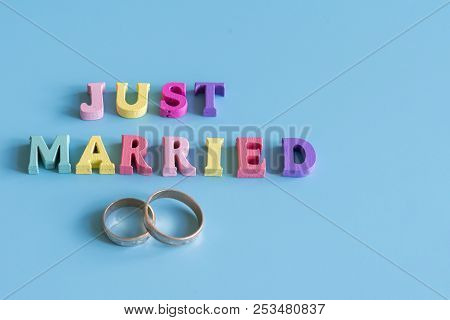Multicolored Inscription Just Married On A Blue Background. Copy Space
