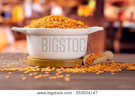 Lot Of Whole Raw Red Lentils In A Ceramic Stewpan With Rustic Wood Kitchen In Background