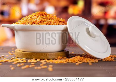 Lot Of Whole Raw Red Lentils In A Ceramic Stewpan With Rustic Wood Kitchen In Background